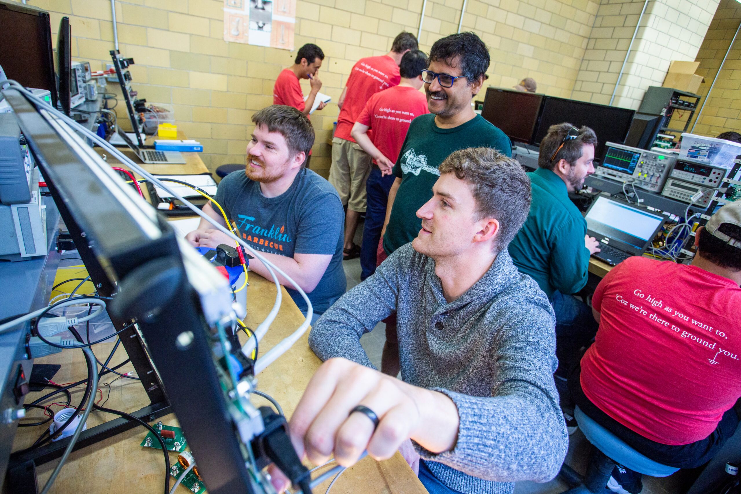 Students engaged in teamwork at a computer in a power electrics lab, demonstrating collaboration in a technical environment.